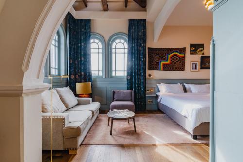 a bedroom with a bed and a couch and a table at Hotel Mercier in Amsterdam