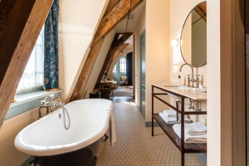 an attic bathroom with a sink and a bath tub at Hotel Mercier in Amsterdam