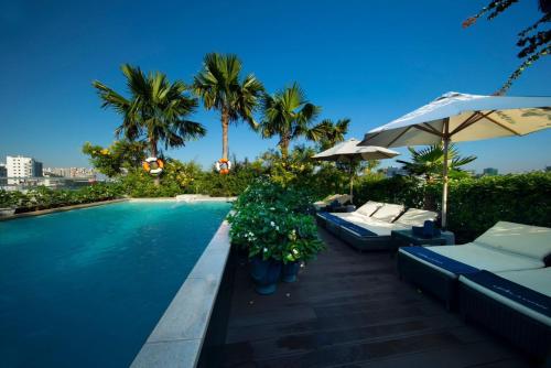 - une piscine avec des parasols et des chaises longues à côté dans l'établissement Alagon City Hotel & Spa, à Hô-Chi-Minh-Ville