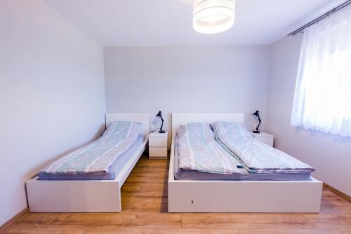 2 Betten in einem Zimmer mit weißen Wänden und Holzböden in der Unterkunft Apartamenty u Ewy in Bodzentyn