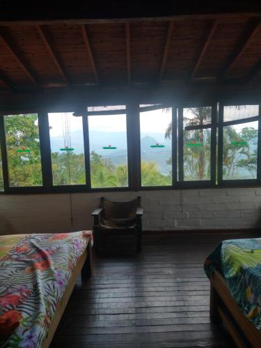 a room with two beds and a chair and windows at Casa Vitall in Líbano