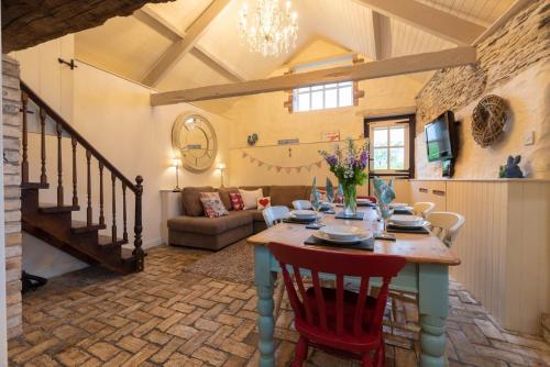 Cette chambre comprend une table avec des chaises et un canapé. dans l'établissement Aggie's Cottage at Higher Mullacott, à Ilfracombe