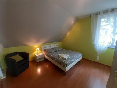 une petite chambre avec un lit et une chaise dans l'établissement Les Aulnays, à Arnage