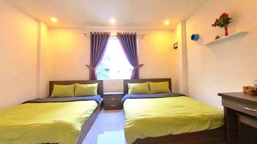 twee bedden in een kleine kamer met een raam bij Uyên House hotel in Da Lat