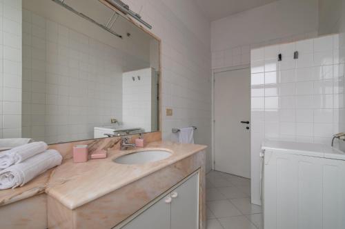 ein Badezimmer mit einem Waschbecken und einem großen Spiegel in der Unterkunft Comfy Flat Steps Away from Siena Station! in Siena