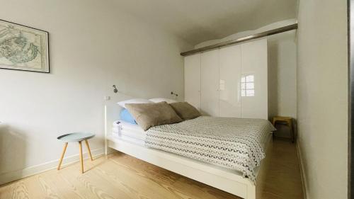 um quarto branco com uma cama e um banco em ApartmentInCopenhagen Apartment 1207 em Copenhague
