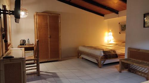 a bedroom with a bed and a dresser in it at Keyani Bungalows Lovina in Lovina
