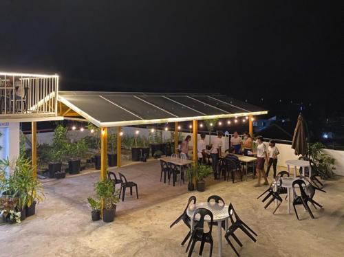 a patio with tables and chairs and people at night at Three U's Pension House in Palompon