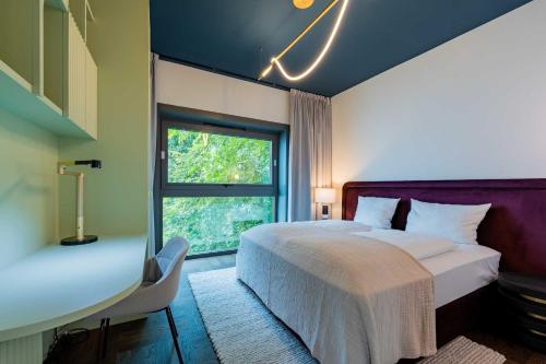 a bedroom with a bed and a window and a desk at The Garden Suites by Suite030 in Berlin