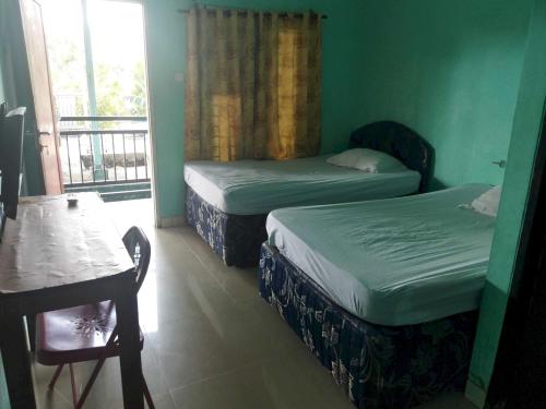 a room with two beds and a table and a window at OYO 93306 Rinjani Guest House in Balikpapan