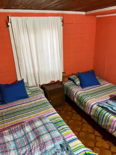 two beds in a room with red walls and a window at Casa en el tabo in San Antonio