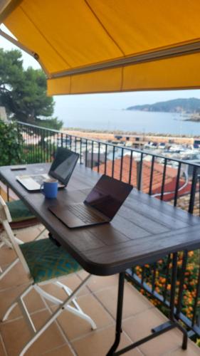 a wooden table with a laptop on top of a balcony at Apartment in front of the sea in Llafranc