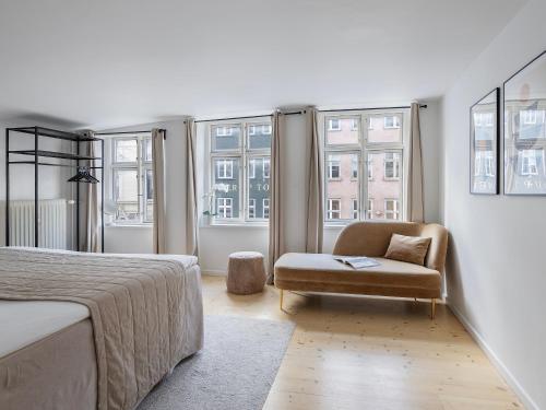 a bedroom with a bed and a chair and windows at Sanders Main - Popular Two-Bedroom Duplex Apartment Next to Magical Nyhavn in Copenhagen
