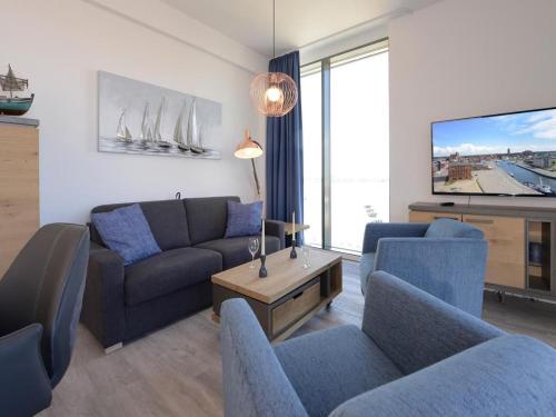een woonkamer met een bank en stoelen en een tv bij Ohlerich Speicher App_ 46 in Wismar