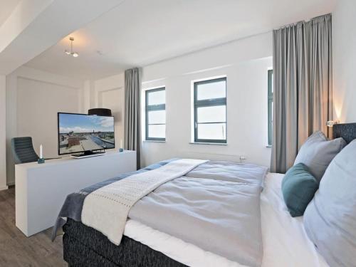 a white bedroom with a large bed and windows at Ohlerich Speicher App_ 47 in Wismar