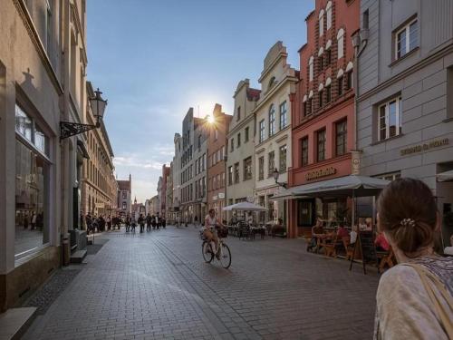 a person riding a bike down a city street at Ohlerich Speicher App_ 47 in Wismar