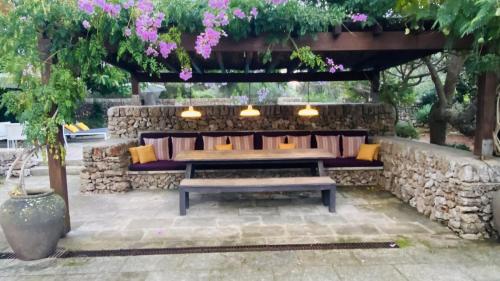 um banco sentado sob uma parede de pedra com flores cor-de-rosa em Holiday Home Casa MADORIA em Sant Climent