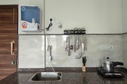 eine Küchentheke mit einer Spüle und Küchenutensilien an der Wand in der Unterkunft Compact yet beautiful 1bhk 001 in Bangalore
