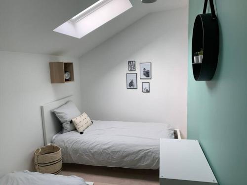 a white bedroom with a bed and a skylight at Petite maison de charme à 10 minutes de Disney ! in Montévrain
