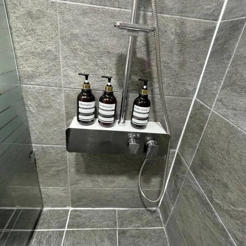 a bathroom with three bottles on a shelf in a shower at Hue Stay in Ansan