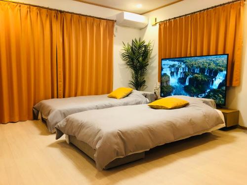 two beds in a room with orange curtains at Kamei House in Tokyo