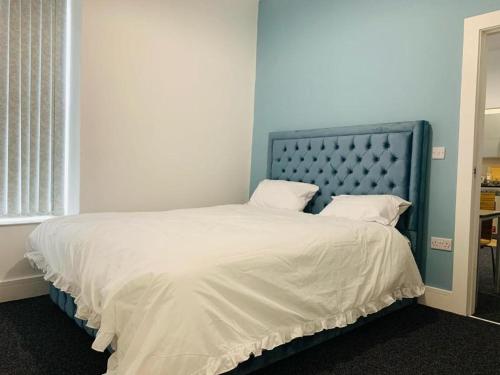 Schlafzimmer mit einem großen Bett mit blauem Kopfteil in der Unterkunft Marina Apartments in Bradford