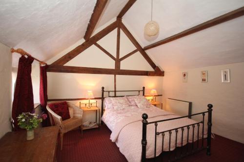 a bedroom with a bed and a chair in a room at The Old House Cottages in Nether Stowey