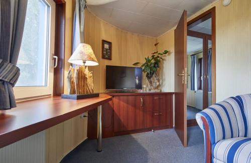 Zimmer mit einem Schreibtisch, einem TV und einer Lampe in der Unterkunft Hotelschiff Stinne in Wustrow