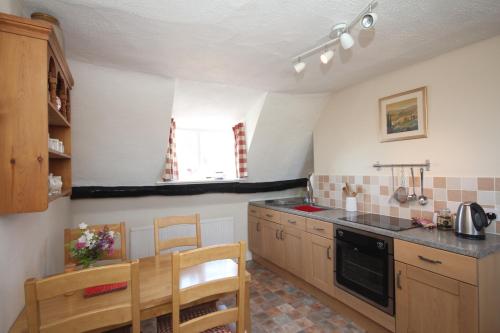 a kitchen with a table and a stove top oven at The Old House Cottages in Nether Stowey