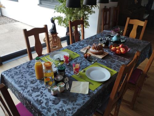 a table with a blue table cloth with food and orange juice at l'écrin des biches in Sainte-Marie-aux-Mines