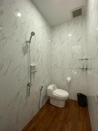 La salle de bains blanche est pourvue d'une douche et de toilettes. dans l'établissement Emerald Guesh House Type Paris Purwokerto, à Purwokerto