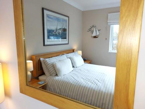Un reflejo en el espejo de una cama en un dormitorio. en A charming 2 bed apartment overlooking the estuary, en Instow