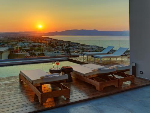 einen Balkon mit Blick auf das Meer bei Sonnenuntergang in der Unterkunft Alectrona Living Crete, Olīvea Luxury Apartment in Platanias