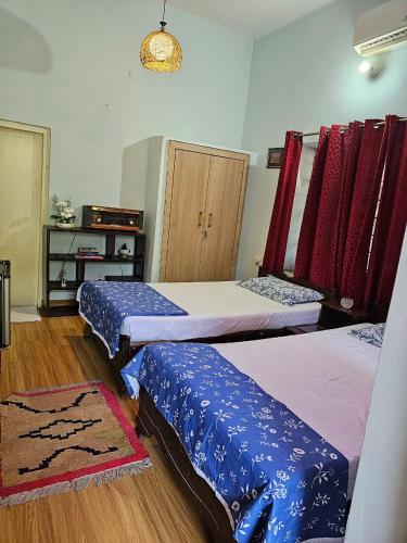 Habitación con 2 camas y sábanas azules y blancas. en Unclesden en Jaipur