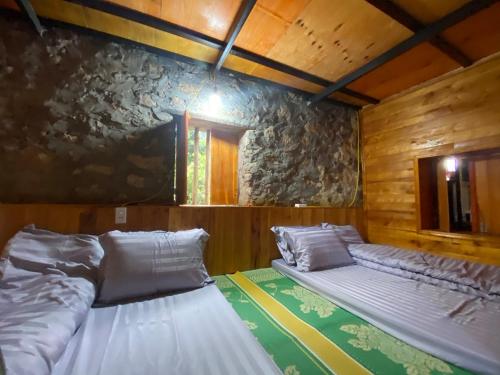 two beds in a room with a stone wall at Triệu Chương Homestay in Cao Bằng