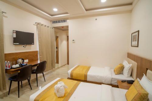 a hotel room with a bed and a desk and a tv at The Triana in Varanasi