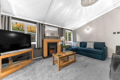 a living room with a blue couch and a tv at Firgarth Lodge in Windermere