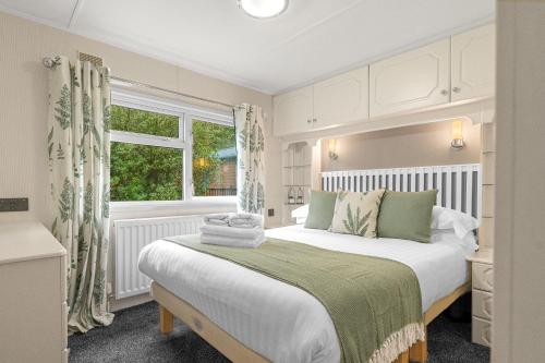 a bedroom with a large white bed and a window at Firgarth Lodge in Windermere