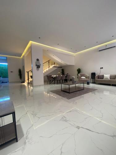 a living room with white marble floors and a table at شاليه اند هوم in Hail