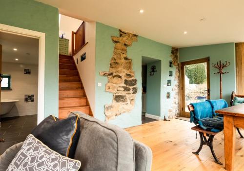 a living room with a stone wall and a table at Penrhiw - a country cottage with mountain views in Newport