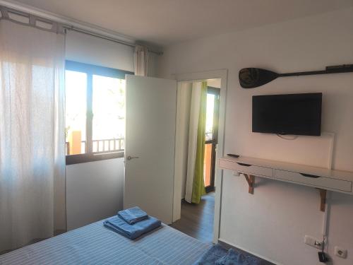 sypialnia z łóżkiem, telewizorem i oknem w obiekcie casa Sun&Sand Corralejo w Corralejo