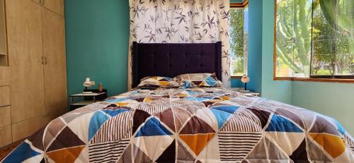 a bed with a colorful quilt on it in a bedroom at Casa elegante y con terraza in Arequipa