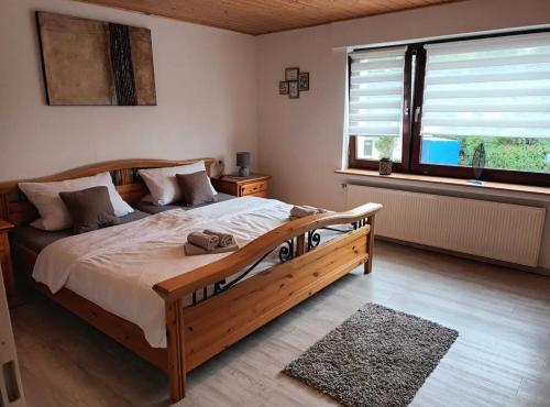 Un dormitorio con una gran cama de madera y una ventana en Zum Rosenhügel, en Hellenthal