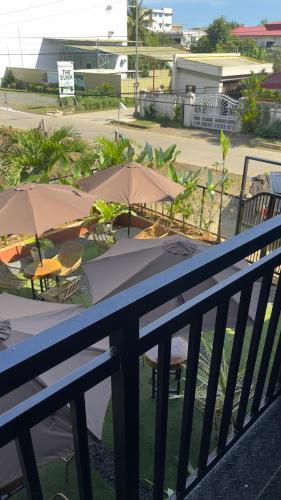 a table with chairs and umbrellas on a balcony at LArtista Hostel in Puerto Princesa City