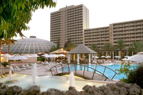 una piscina con sombrillas y un hotel en Rodos Palace Hotel, en Ixia