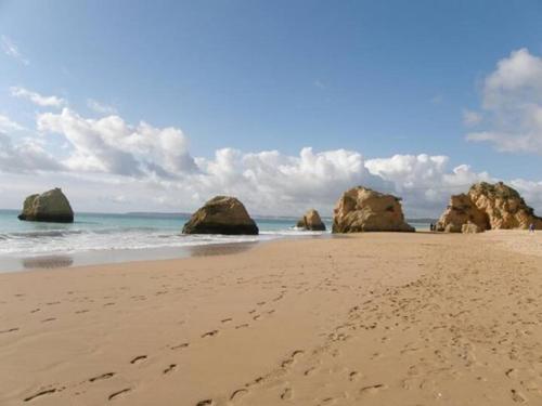 a sandy beach with some rocks in the water at ALVOR VILLAGE BY THE SEA in Alvor