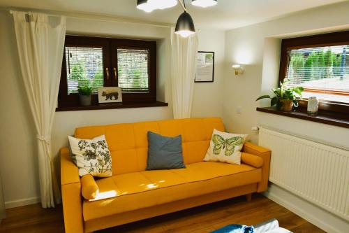 an orange couch in a living room with windows at Gościniec Skorusa in Kościelisko