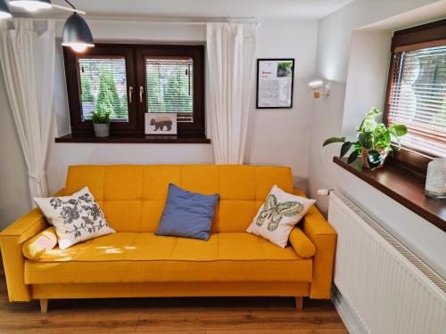 a yellow couch in a living room with windows at Gościniec Skorusa in Kościelisko