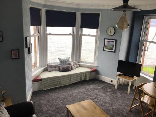 a living room with a bed and two windows at Bellevue Bute, Luxury 2 bedroom sea view flat in Rothesay