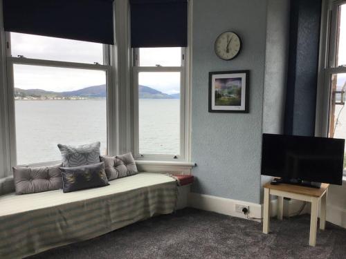 a living room with a bed and a clock on the wall at Bellevue Bute, Luxury 2 bedroom sea view flat in Rothesay